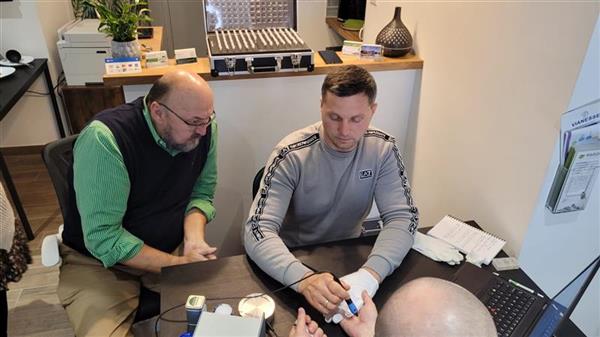 Bio-resonance EAV session in progress — practitioner working with client using bioresonance diagnostic device and laptop